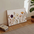 Floor-leaning farmhouse botanical canvas print beside books and a potted plant