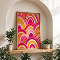 Framed pink and orange geometric rainbow poster in a bright interior