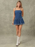 Full front view of embroidered denim sundress styled with white cowboy boots