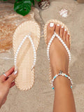 Overhead cream woven-look flip-flops with white pearl straps at a beach set