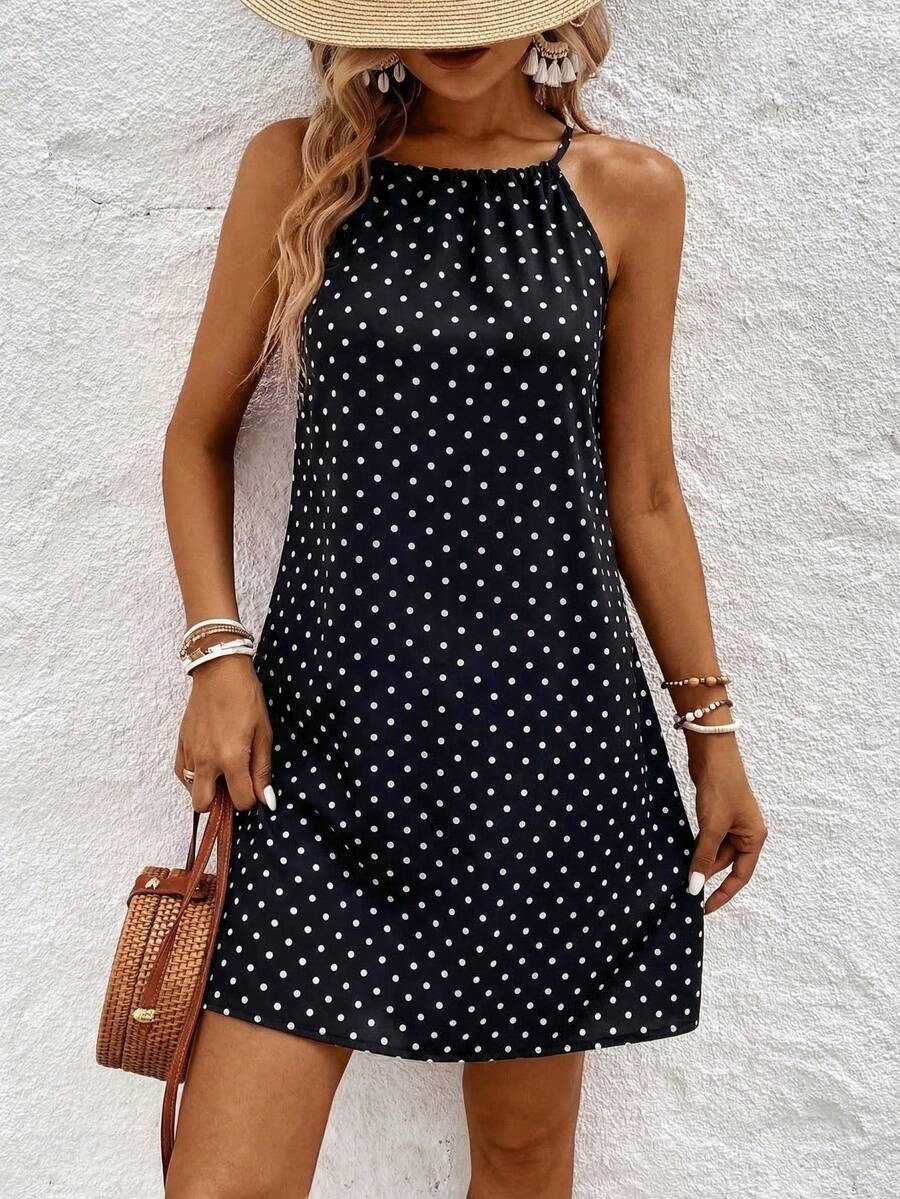 Front three-quarter view of black and white polka dot halter mini dress outdoors