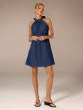 Full front view of dark indigo A-line denim mini dress styled with black sandals