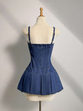 Back view of blue denim mini dress showing adjustable straps and box pleats