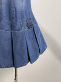 Close-up of blue denim mini dress pleated hem and antique-brass side ring detail