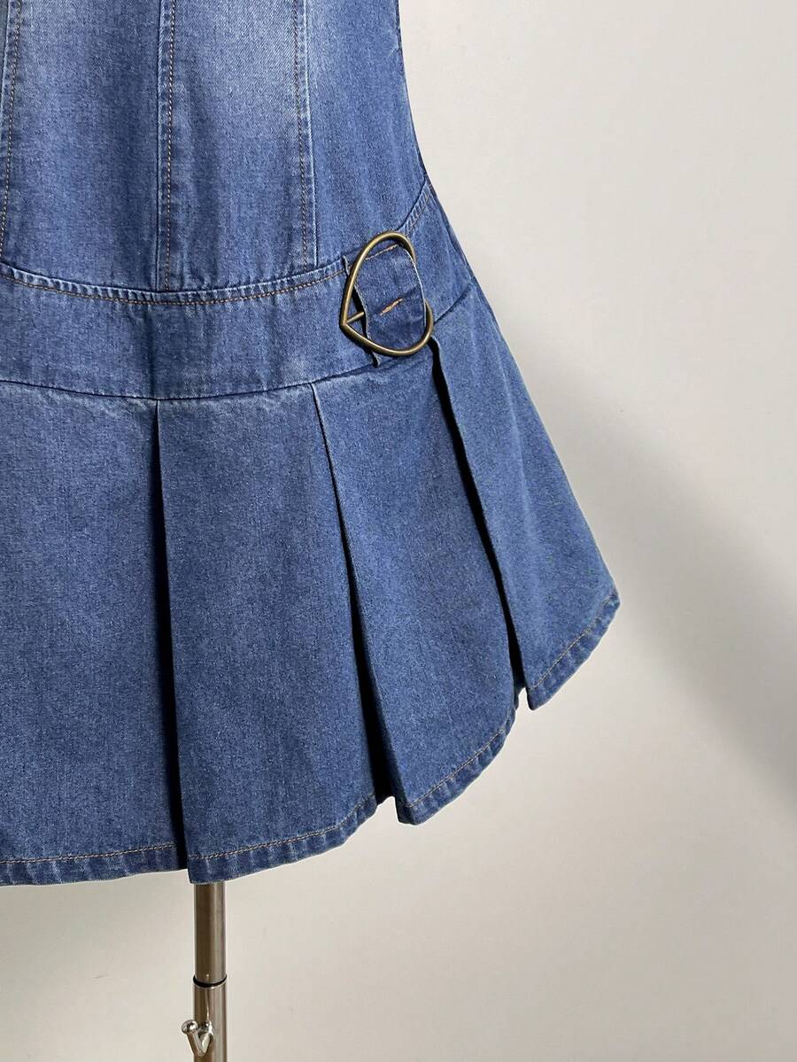 Close-up of blue denim mini dress pleated hem and antique-brass side ring detail