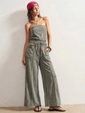 Front three-quarter view of sage strapless jumpsuit with hand in patch pocket for casual styling