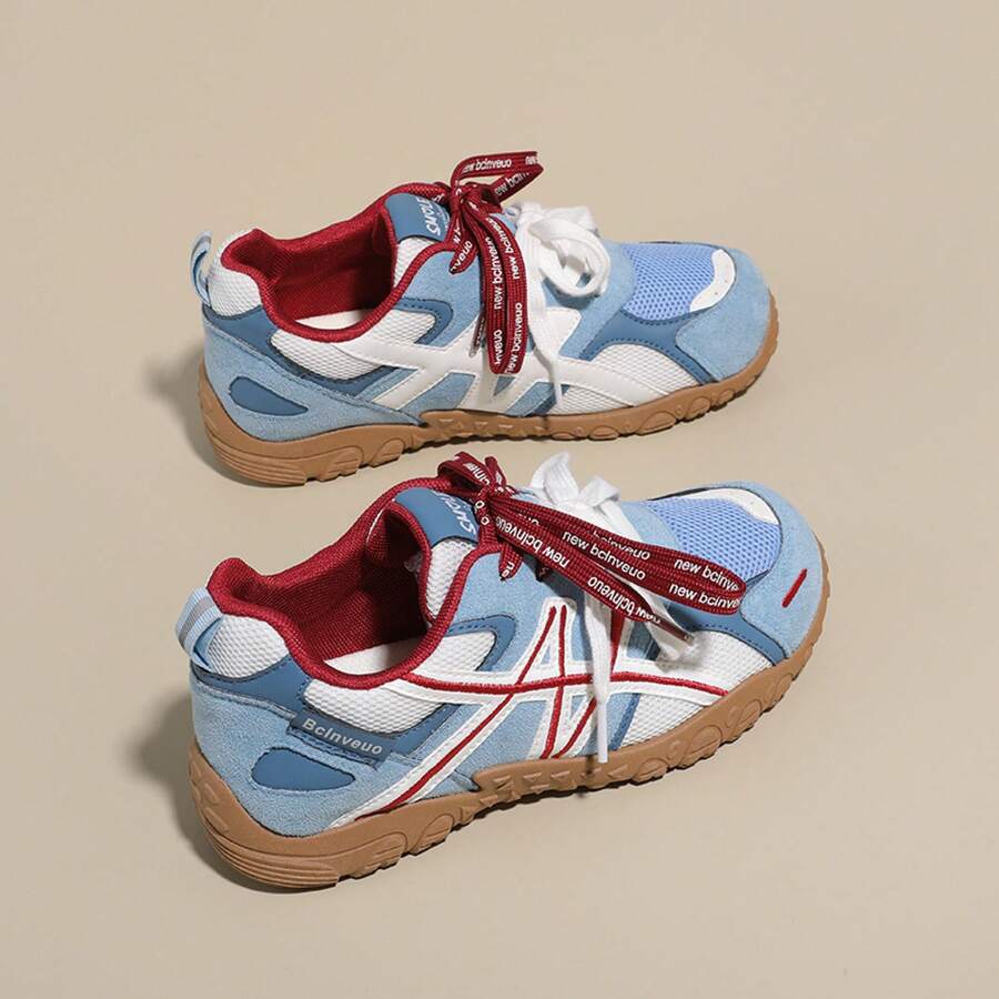 Side view of light blue, white, and red colorblock sneaker with white laces and gum tread sole