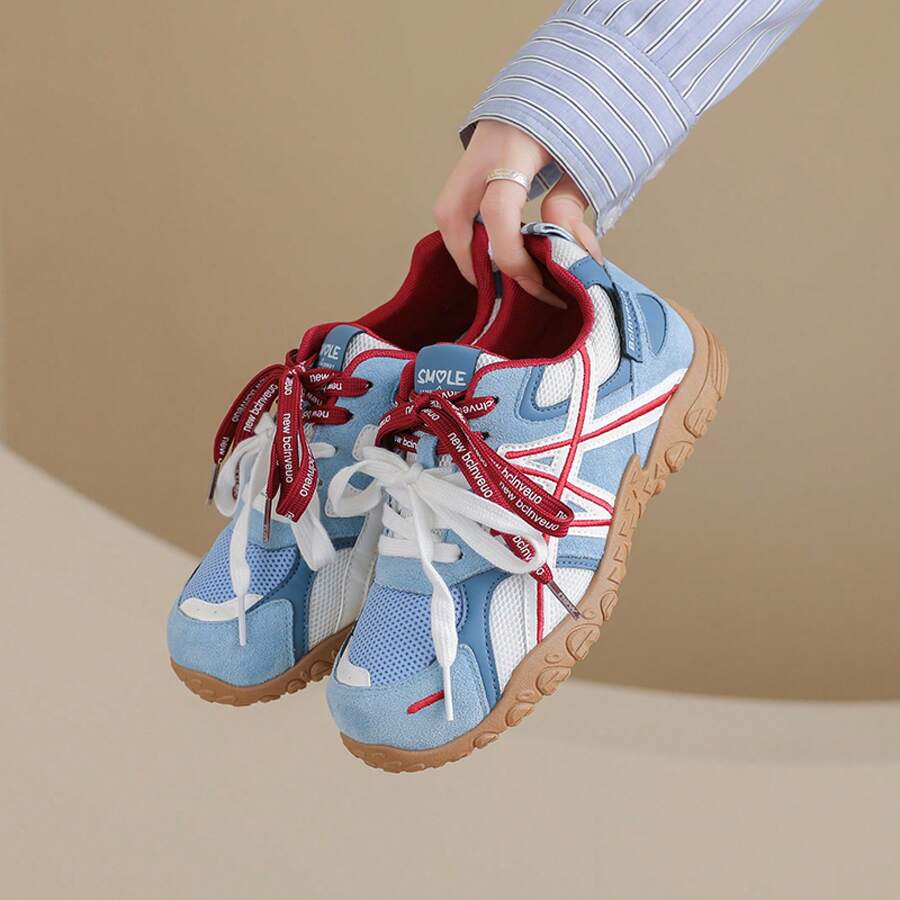 Suspended front-side view of light blue colorblock sneaker with red ribbon and gum sole