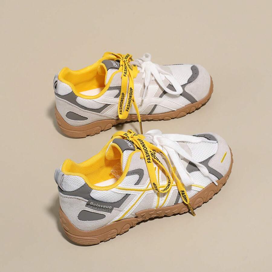 Overhead view of white, gray, and yellow mesh colorblock sneaker with yellow ribbon detail