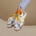 Suspended front-side view of white and yellow colorblock sneaker with gum tread sole