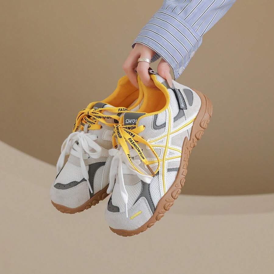 Suspended front-side view of white and yellow colorblock sneaker with gum tread sole