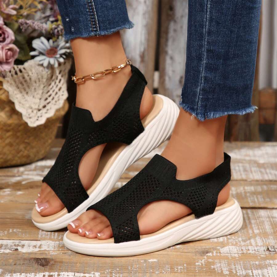 Rear side view of black mesh wedge sandals showing open heel and ridged sole