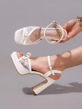 Close-up of white open toe platform sandal with pearl bow and sheer lace vamp
