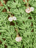 Close up green raffia weave with faux pearl and pink shell charm dangles