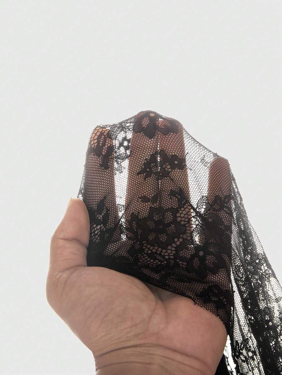 Close view of semi-sheer black floral lace fabric used on asymmetrical mini dress