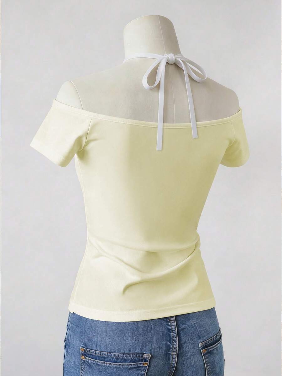 Back view of pale yellow off-shoulder halter top with white neck ties and jeans