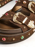 Close-up of gold buckles and multicolor gems on brown platform sandals
