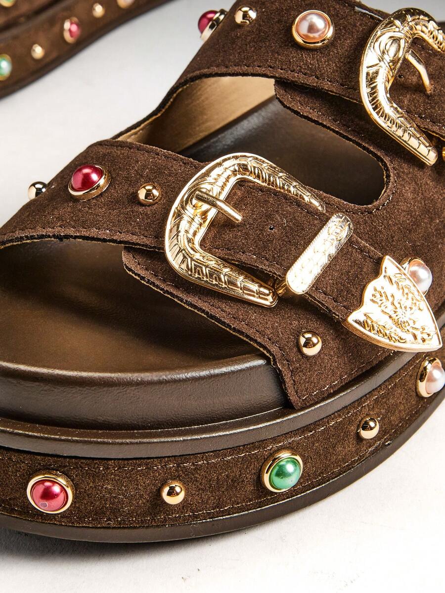 Close-up of gold buckles and multicolor gems on brown platform sandals