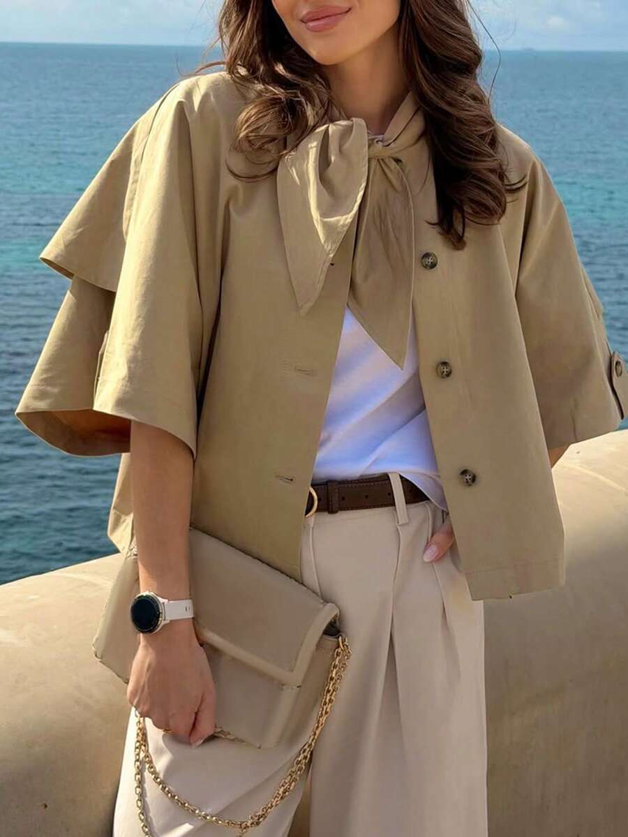 Khaki cape jacket with bow tie and front buttons, seaside view
