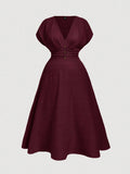 A dark burgundy midi dress with a V-neckline, short puff sleeves, a gathered waist with button details, and a flared skirt, shown against a light gray background.