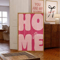 Pink Welcome Home typography print in a gold-tone frame styled in a living room
