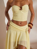 Close detail view of light yellow ruched bandeau top and high-slit mesh maxi skirt two-piece set for beach vacation styling