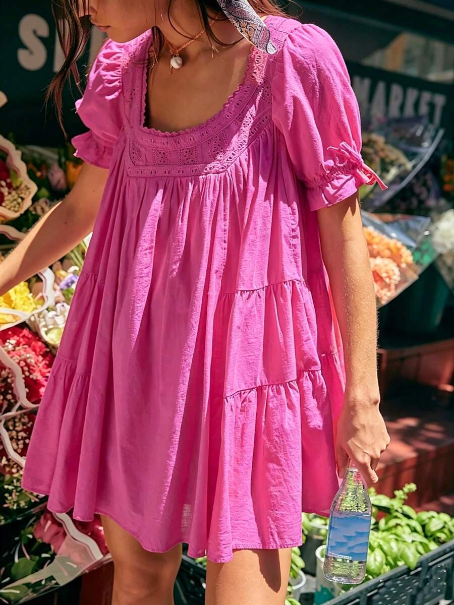 Front three-quarter view of fuchsia eyelet babydoll mini dress at a produce market