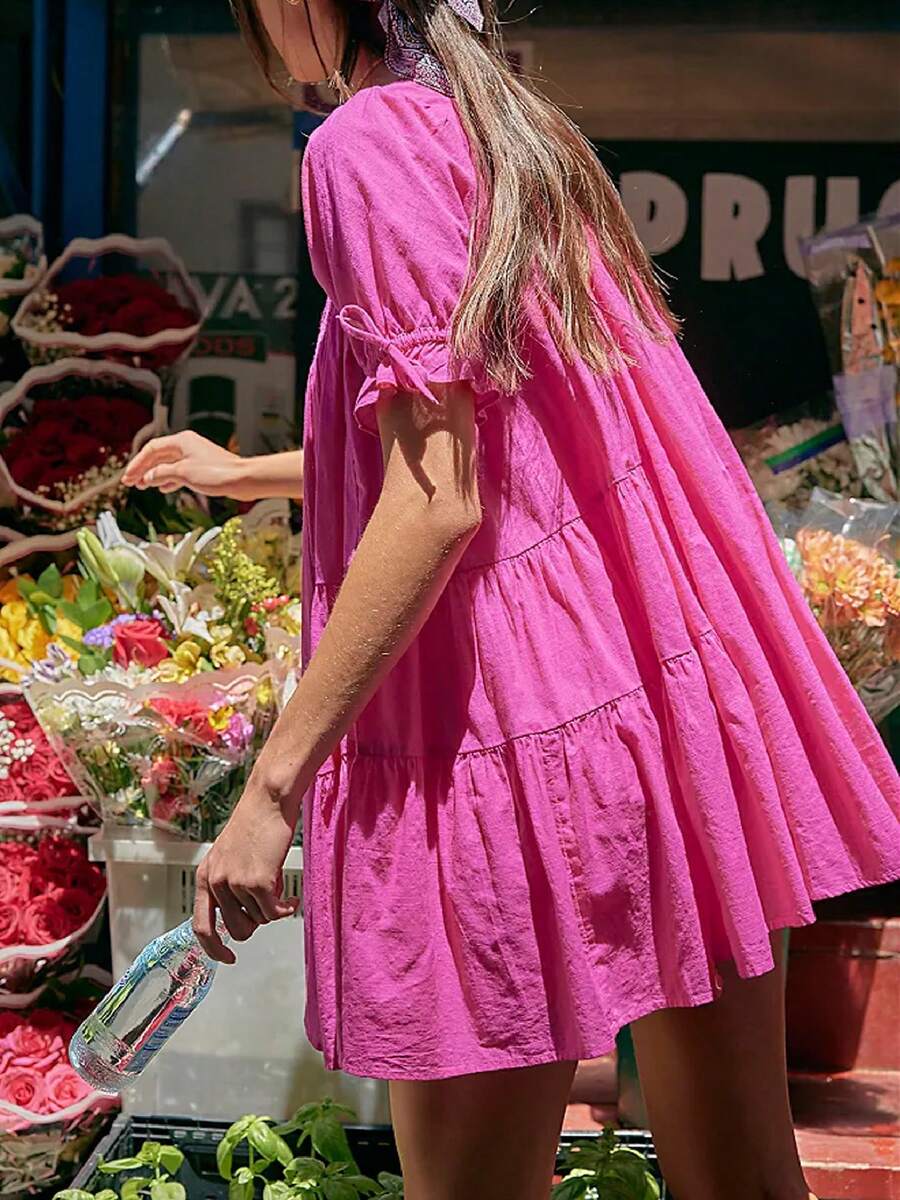 Front three-quarter view of fuchsia eyelet babydoll mini dress at a produce market