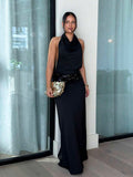 Three quarter front view of black satin look halter dress with slim maxi silhouette