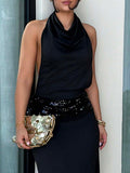 Close up view of black halter dress with cowl neckline and sequin waist detail