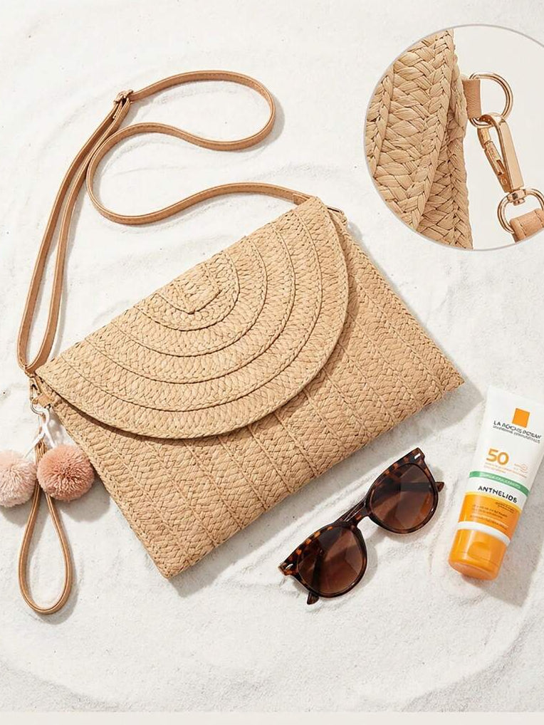 Flat lay front view of beige raffia envelope bag with foldover flap and tan strap
