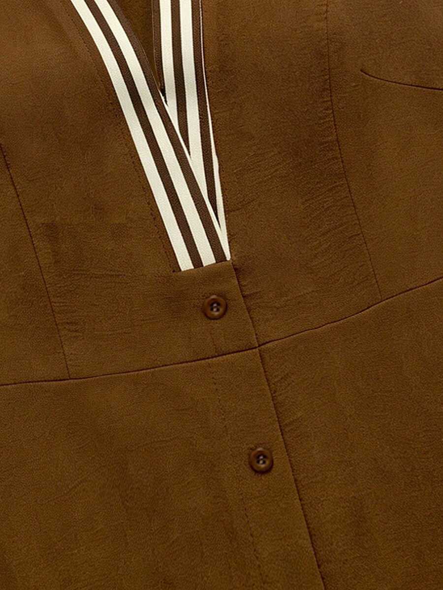 Close detail of brown button placket with striped trim and textured woven fabric