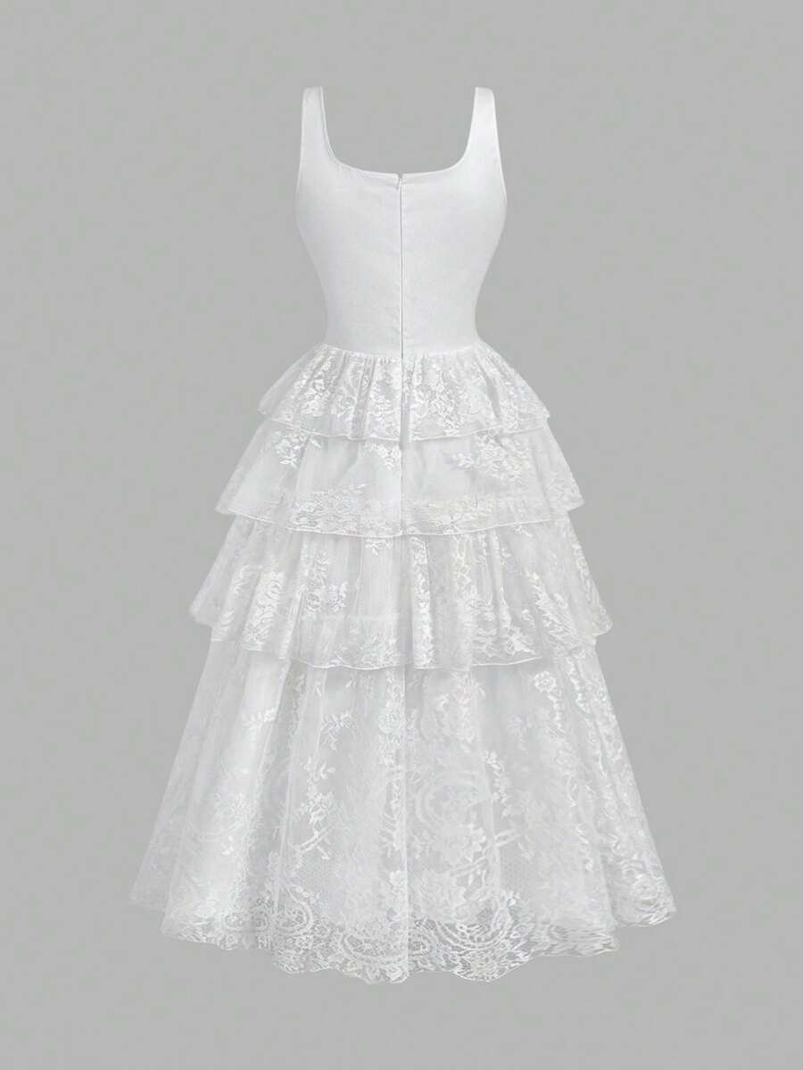 Full front view of white lace tiered midi dress beside a garden fountain