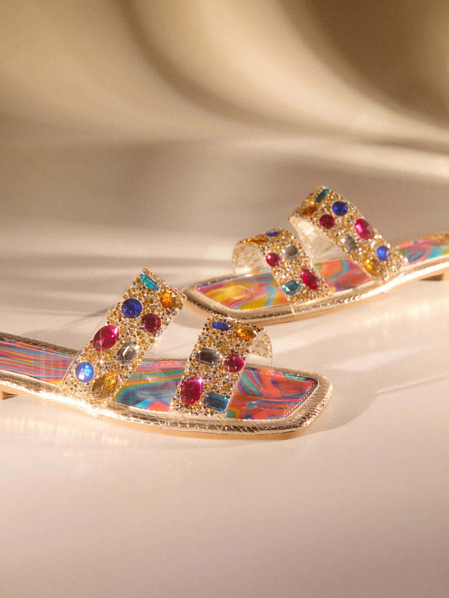 Step into summer with these vibrant rhinestone-embellished flat sandals, designed for effortless style. Featuring colorful crystal accents that catch the light, these versatile sandals transition seamlessly from beach days to casual outings. The comfortable flat sole keeps you supported through all your warm-weather adventures, while the eye-catching embellishments add a touch of sparkle to any outfit. Perfect for poolside lounging, weekend getaways, or everyday wear when you want to shine.