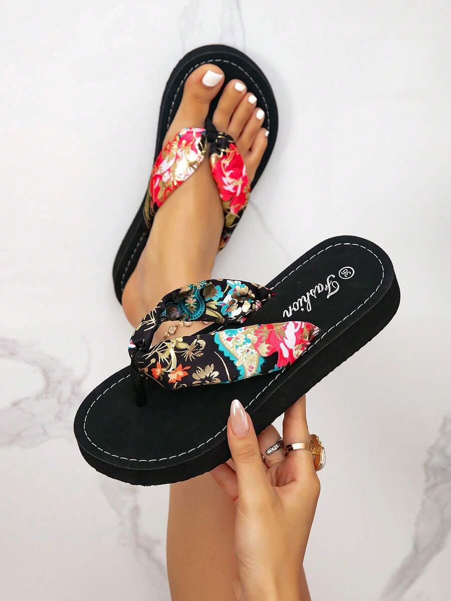 Overhead black floral paisley flip-flops shown worn and held by a marble backdrop