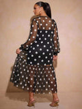 Rear view of black and white polka dot long dress with sheer sleeves and flowing gathered hem