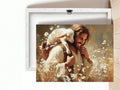A framed canvas print leaning against a white wall on a light wood floor, showing a warm-toned painting of Jesus embracing a white lamb surrounded by small white flowers. The back of the canvas is visible behind it.