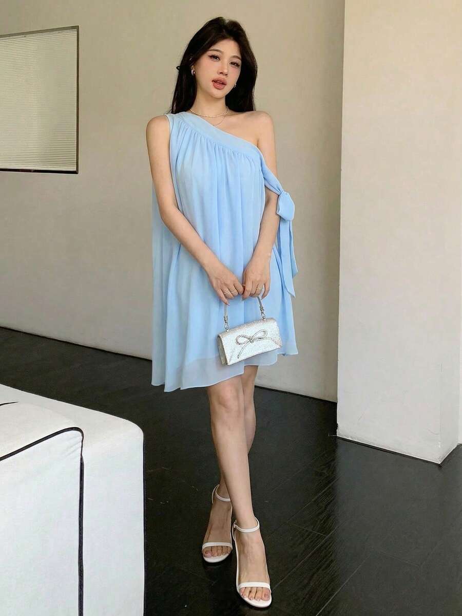 Styled view of light blue one-shoulder A-line mini dress showing visible color, print, and silhouette