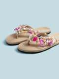 Close low view of beige flat sandals with starfish, seahorse, and pearl details