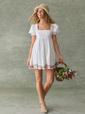 White fit-and-flare mini dress with embroidered floral hem