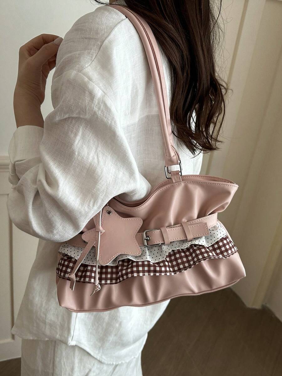 Blush pink ruffled shoulder tote with gingham and polka dot trim, belt detail, and star charm hanging on chrome rack