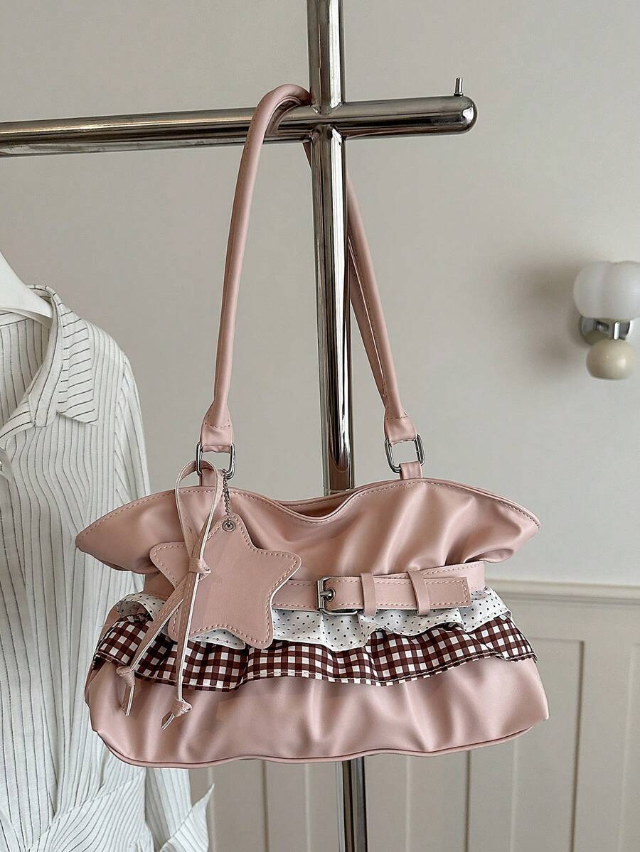 Blush pink ruffled shoulder tote with gingham and polka dot trim, belt detail, and star charm hanging on chrome rack