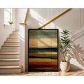 Stairwell view of framed earth tone abstract wall art leaning beside plant