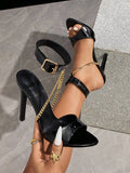 Black patent peep-toe stiletto sandal with ankle buckle and gold chain