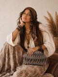 Model seated with black and taupe printed boho clutch on lap in resort styling