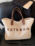 Front studio view of beige crochet tote bag with brown handles and TOTE BAG lettering