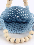 Model carrying light blue crochet mesh handbag with wooden bead handles and tassel fringe