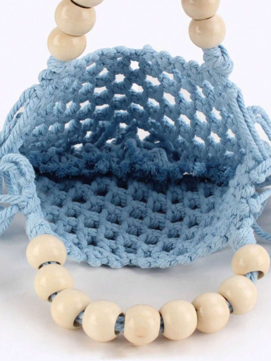 Model carrying light blue crochet mesh handbag with wooden bead handles and tassel fringe