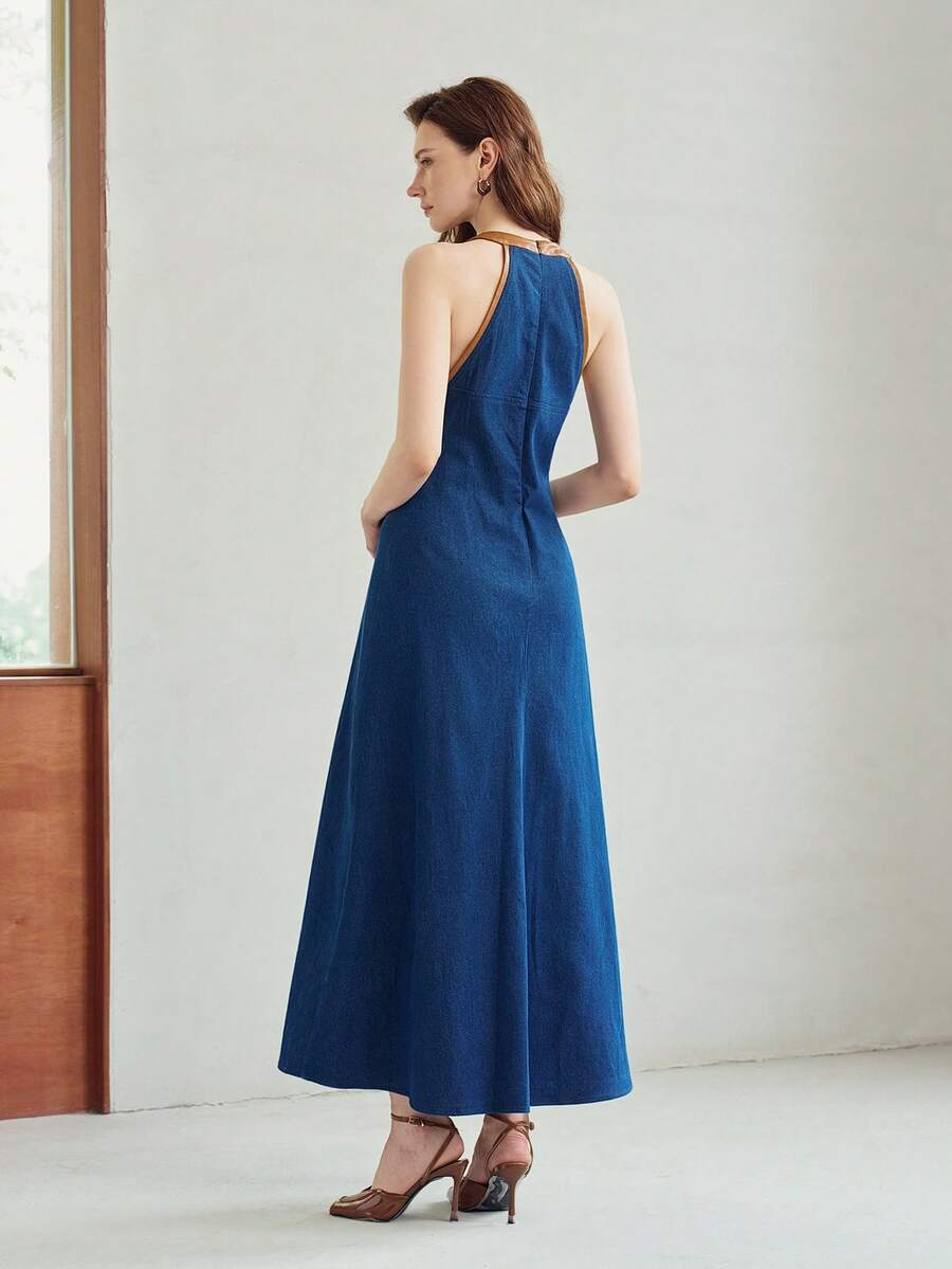 Rear three-quarter view of deep blue sleeveless A-line denim maxi dress in an indoor setting