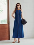 Full front view of deep blue halter denim maxi dress styled with brown heels indoors